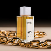 Perfume divain-973 rodeado por uma corrente de ouro que dá uma sensação de luxo.