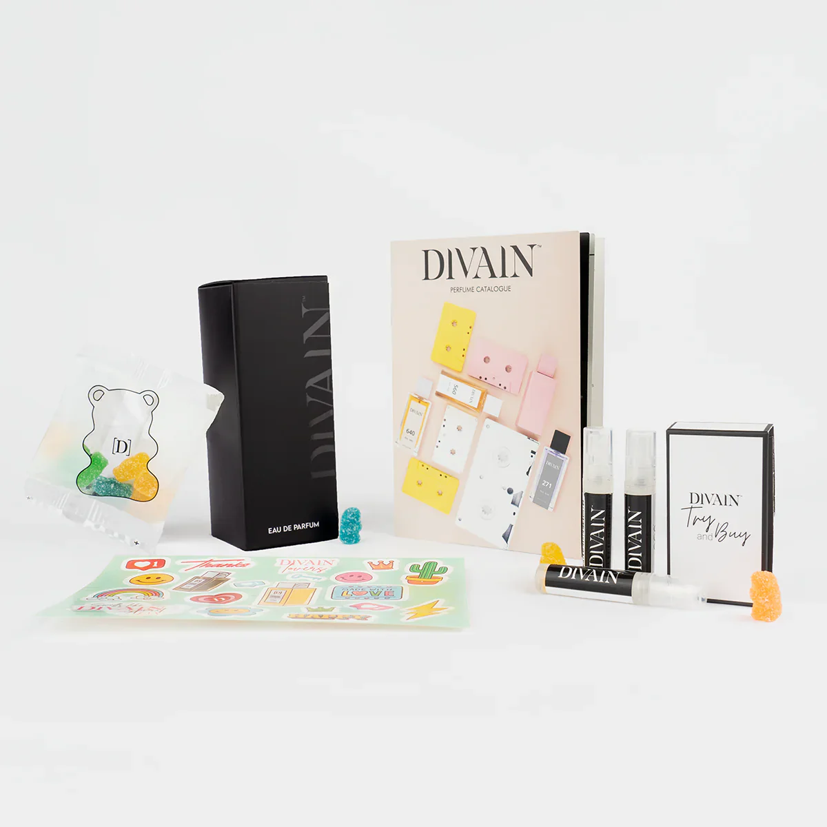 Pacote divain aberto contendo o perfume divain-048, adesivos e balas
